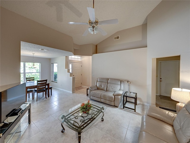 living room featuring light tile patterned floors, a textured ceiling, vaulted ceiling, and ceiling fan