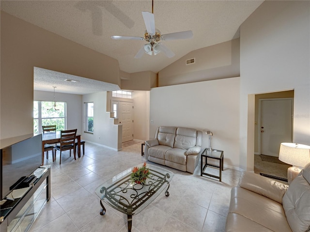 living room with ceiling fan, high vaulted ceiling, a textured ceiling, and light tile patterned floors