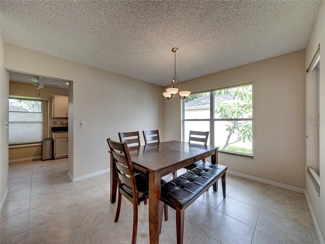 dining space featuring ceiling fan with notable chandelier, light tile patterned floors, and a textured ceiling