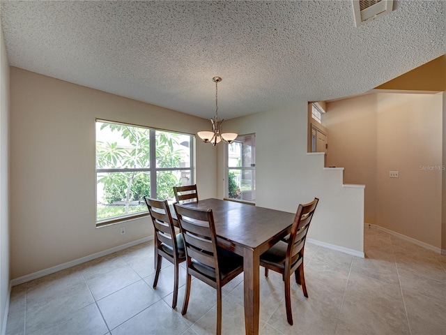 tiled dining space featuring a notable chandelier and a textured ceiling