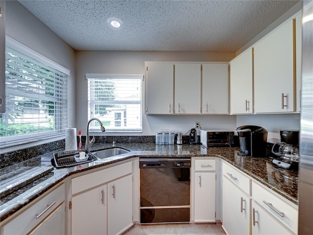 kitchen featuring black dishwasher, white cabinetry, a wealth of natural light, and dark stone countertops