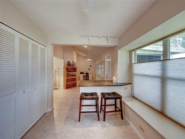 kitchen with hanging light fixtures, kitchen peninsula, track lighting, vaulted ceiling, and a breakfast bar area