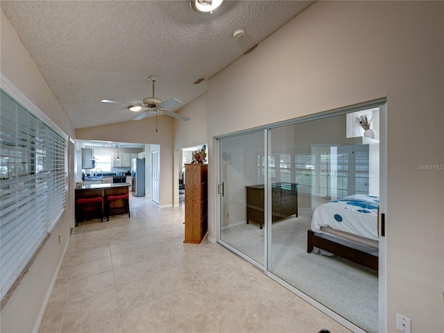 interior space with light tile patterned flooring, a textured ceiling, and vaulted ceiling