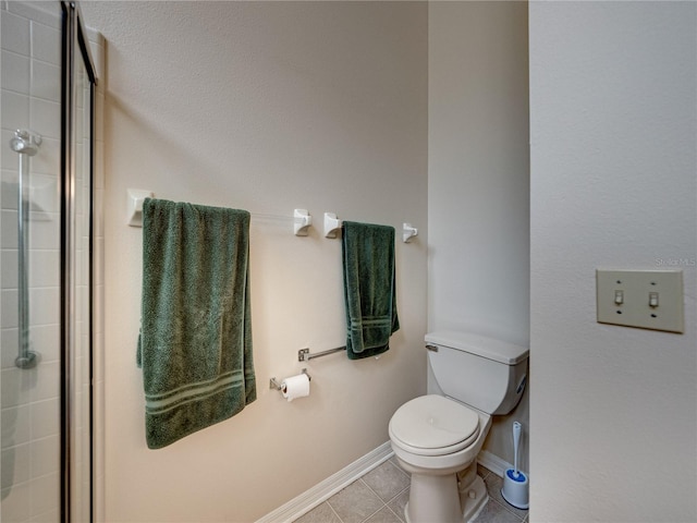 bathroom featuring toilet, an enclosed shower, and tile patterned flooring