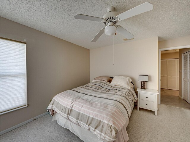 bedroom featuring light carpet, a textured ceiling, multiple windows, and ceiling fan