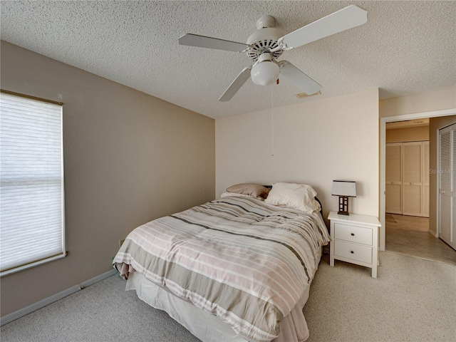 bedroom with ceiling fan, light colored carpet, and a textured ceiling