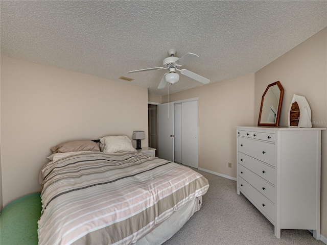 carpeted bedroom with ceiling fan, a textured ceiling, and a closet