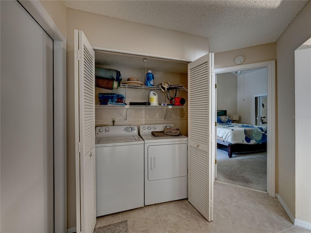 clothes washing area featuring washer and dryer, light colored carpet, and a textured ceiling