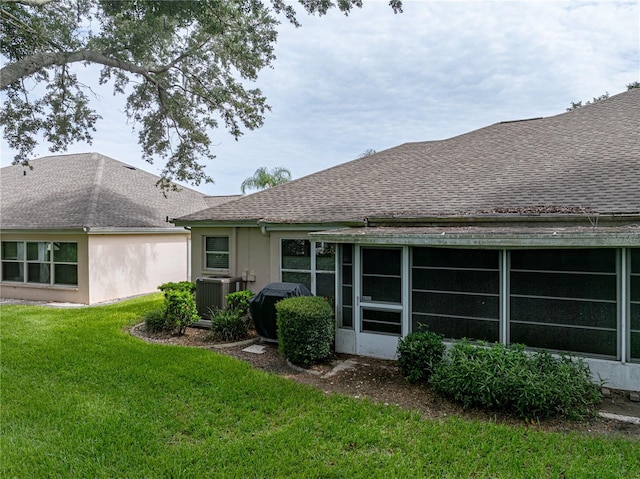 back of house with cooling unit, a sunroom, and a lawn