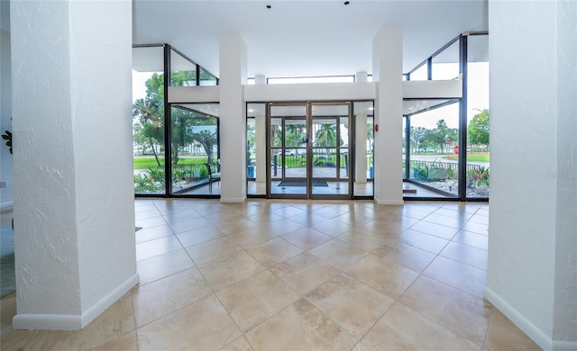 unfurnished room featuring light tile patterned floors and a towering ceiling