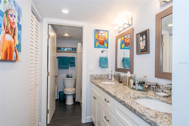 bathroom featuring tile patterned floors, toilet, and dual bowl vanity