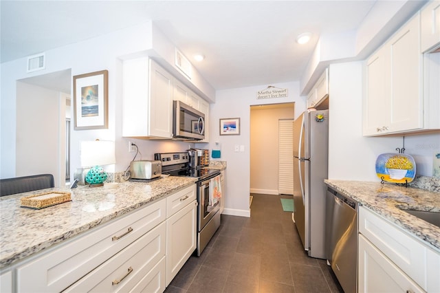 kitchen featuring appliances with stainless steel finishes, white cabinets, and dark tile patterned flooring