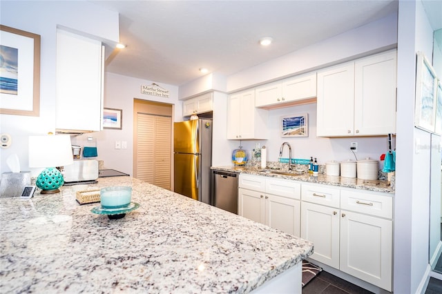 kitchen with sink, light stone countertops, stainless steel appliances, and white cabinetry