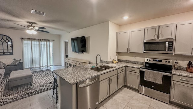 kitchen featuring light tile patterned flooring, kitchen peninsula, ceiling fan, and stainless steel appliances