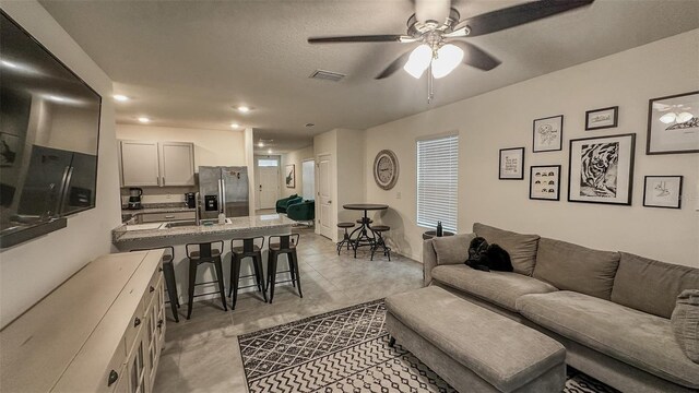 living room featuring sink, light tile patterned floors, and ceiling fan