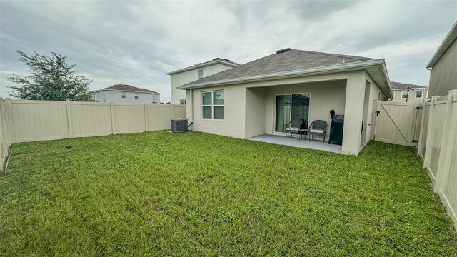 rear view of property with cooling unit, a lawn, and a patio area