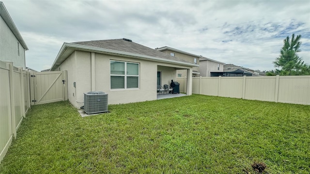 rear view of house with central air condition unit, a patio area, and a yard