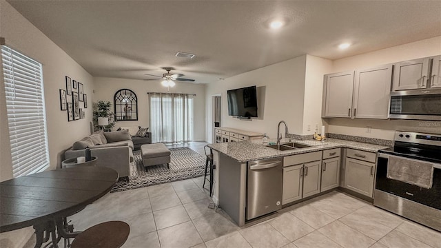 kitchen with ceiling fan, stainless steel appliances, sink, and kitchen peninsula