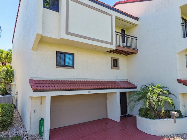 exterior space with central AC unit, a garage, and a balcony