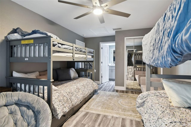 bedroom featuring ensuite bath, hardwood / wood-style floors, ceiling fan, and a closet