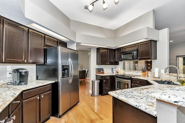 kitchen with appliances with stainless steel finishes, sink, kitchen peninsula, light hardwood / wood-style floors, and rail lighting