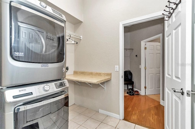 laundry room featuring stacked washer / dryer and light wood-type flooring