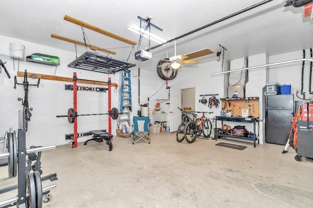 garage with black refrigerator, a workshop area, and a garage door opener