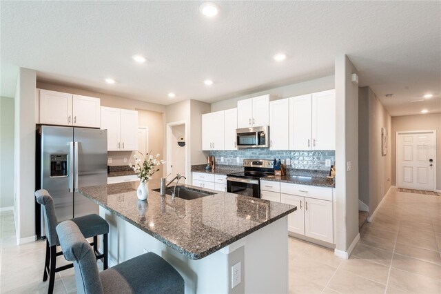 kitchen featuring appliances with stainless steel finishes, dark stone countertops, and white cabinetry