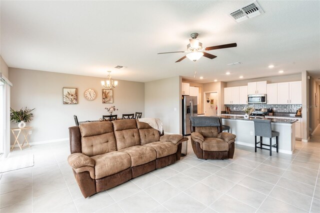 living room with ceiling fan with notable chandelier and light tile patterned floors