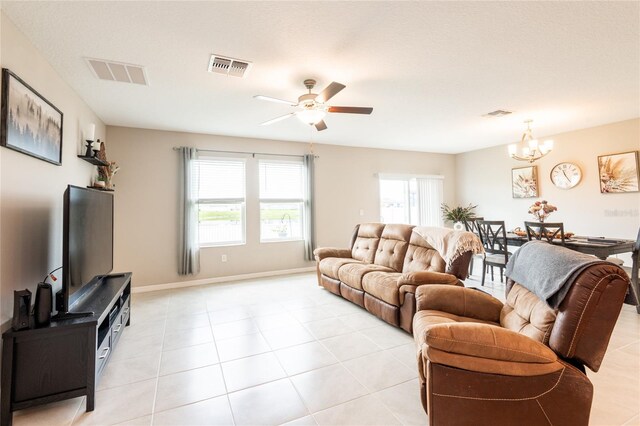 living room featuring light tile patterned flooring and ceiling fan with notable chandelier