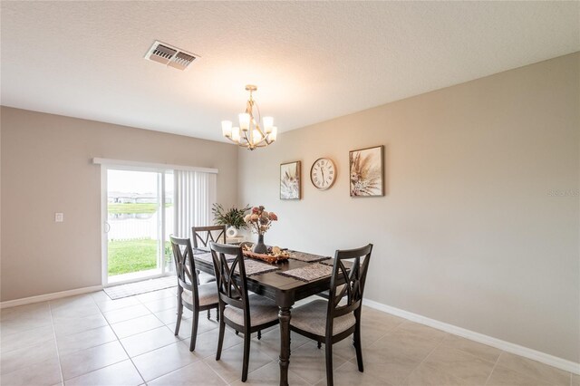 dining space featuring light tile patterned flooring, a chandelier, and a textured ceiling