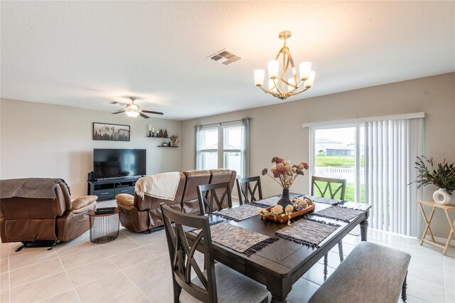 dining space with light tile patterned flooring, plenty of natural light, and ceiling fan with notable chandelier