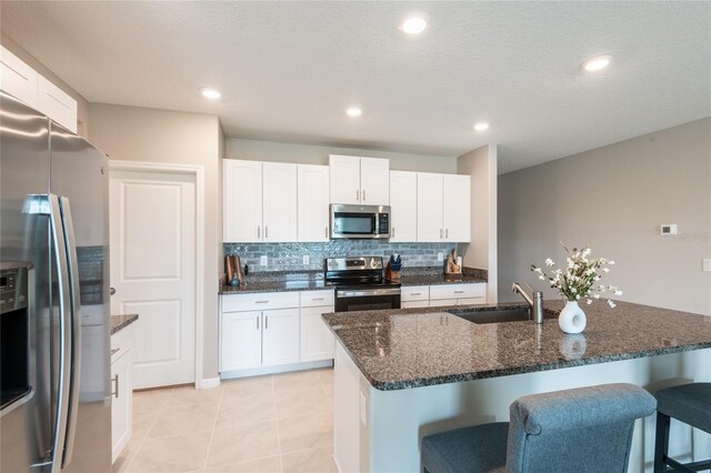 kitchen featuring light tile patterned floors, white cabinets, stainless steel appliances, and sink