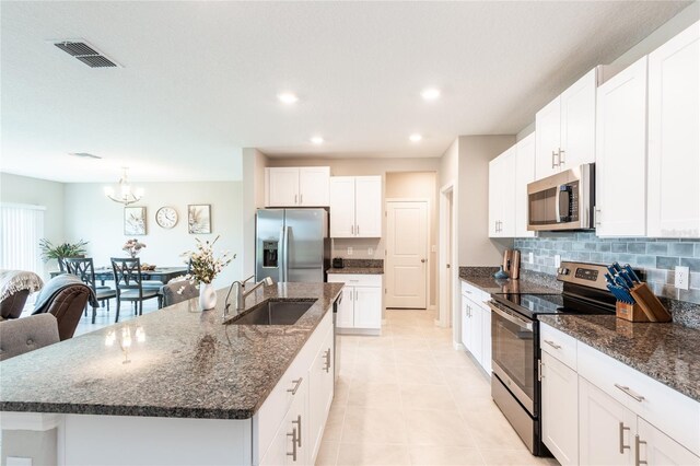 kitchen with a center island with sink, light tile patterned flooring, appliances with stainless steel finishes, a chandelier, and sink