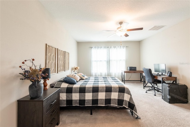 bedroom featuring a textured ceiling, light colored carpet, and ceiling fan