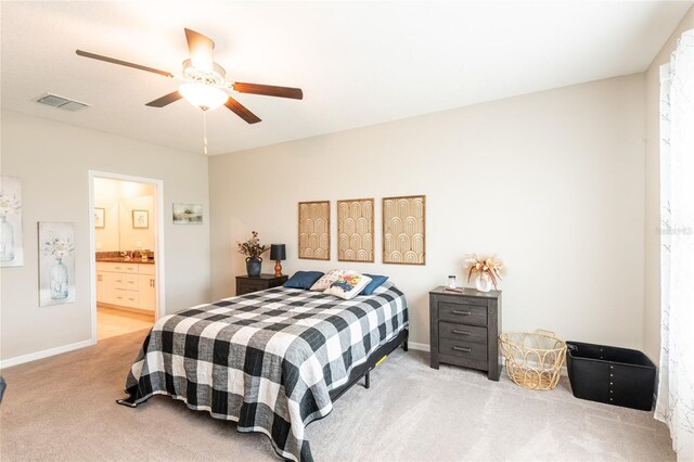 bedroom with ceiling fan, ensuite bath, and light carpet