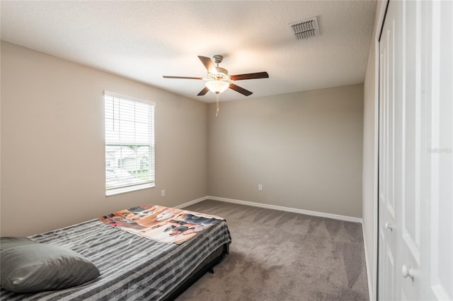 carpeted bedroom with ceiling fan and a textured ceiling