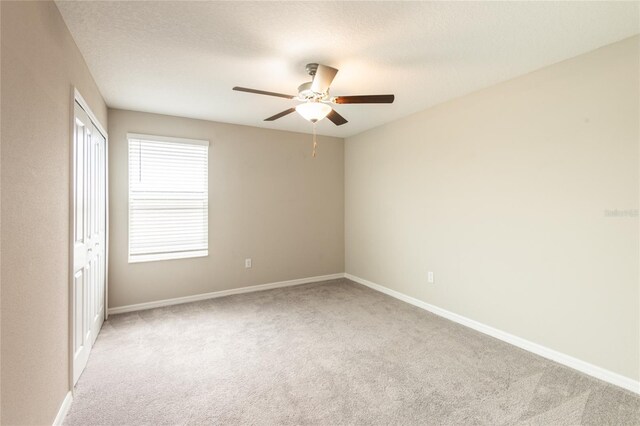 empty room with ceiling fan and light carpet