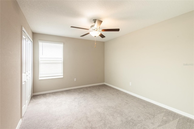 unfurnished room featuring ceiling fan, light colored carpet, and a textured ceiling