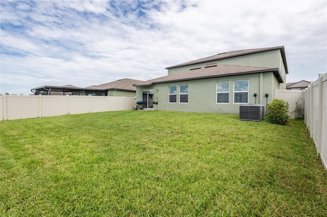 rear view of house featuring cooling unit and a lawn