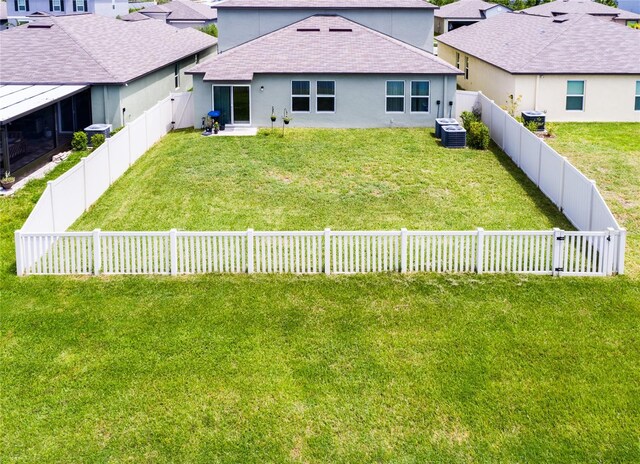 back of house featuring cooling unit and a lawn