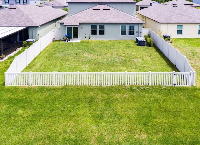 back of property featuring cooling unit and a yard