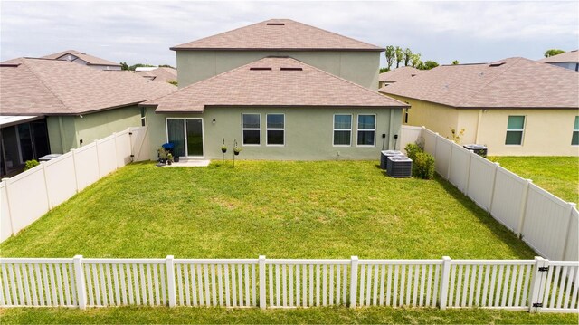 back of house with central AC and a lawn