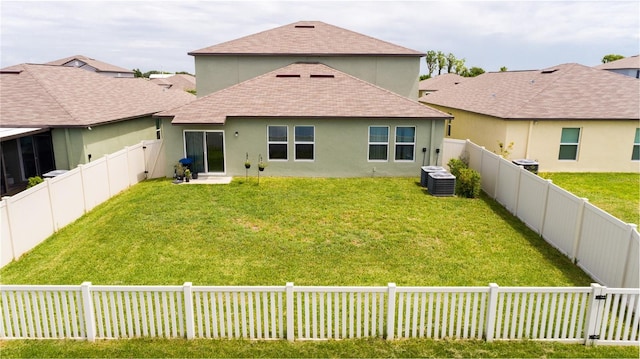 back of house with central AC unit and a lawn