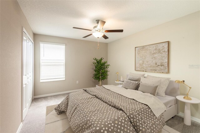 bedroom with ceiling fan, a closet, and light colored carpet