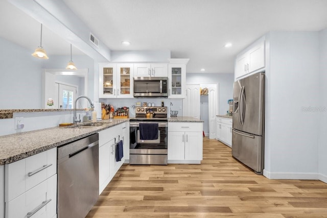 kitchen with light stone counters, white cabinets, stainless steel appliances, and sink