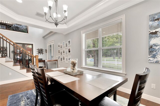 dining area featuring an inviting chandelier, hardwood / wood-style floors, and a tray ceiling