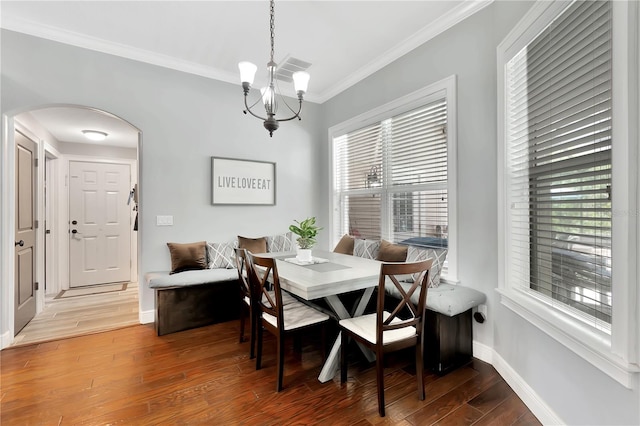 dining space with crown molding, wood-type flooring, and a notable chandelier