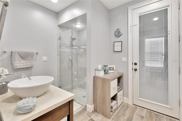 bathroom featuring a shower with door and vanity