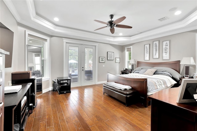 bedroom featuring hardwood / wood-style floors, access to exterior, a raised ceiling, crown molding, and french doors